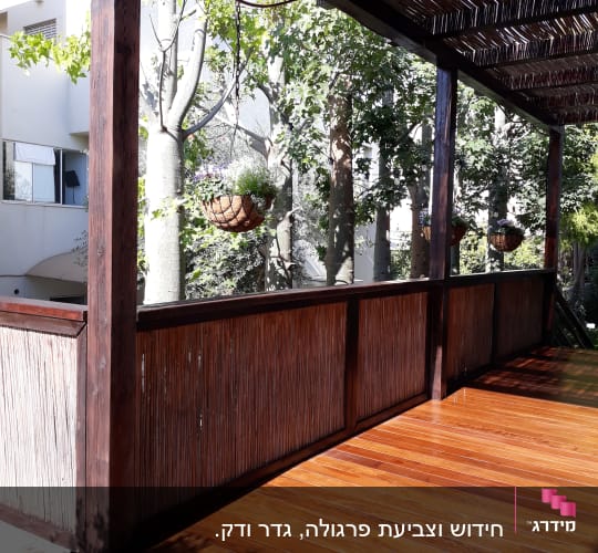 מרפסת עץ עם גג קנים ועציצים תלויים